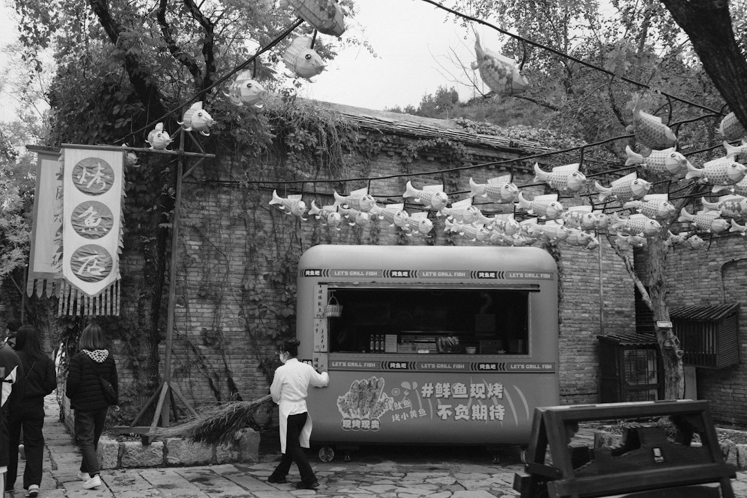 A food truck parked near a stone building with trees