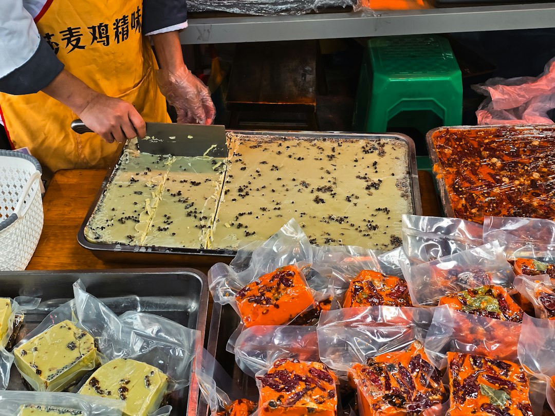 A person in an apron cutting blocks of green hot pot base in Chengdu