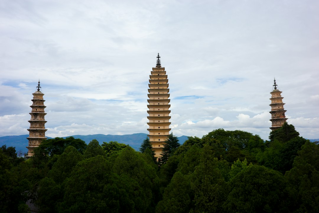 Three ancient pagodas tower above lush trees and distant mountains