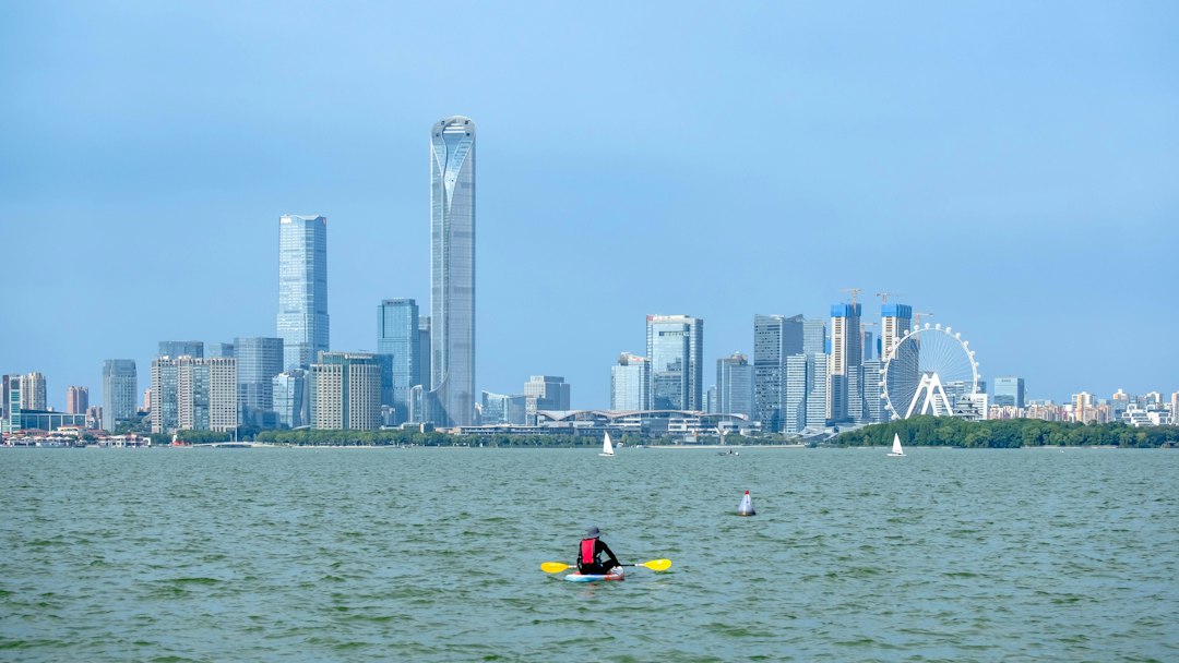 A person kayaking on Jinji Lake with the Suzhou skyline in the background